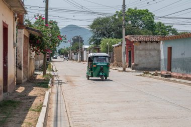 SAN BARTOLO COYOTEPEC, OAXACA - 25 Mayıs 2022: San Bartolo Coyotepec, Oaxaca, Meksika 'da moto taksi ve tipik evler ile bir cadde görüntüsü