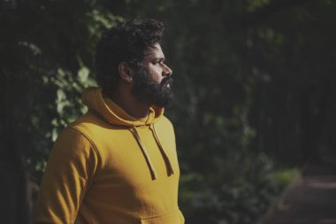 Yeşil halk parkında dinlenen yeşil arka planı olan Hintli erkek model.