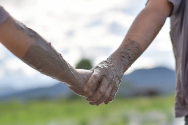 El ele tutuşan iki çocuğun çamurlu çamuru. Karşılıklı yardım ve dostluk kavramı