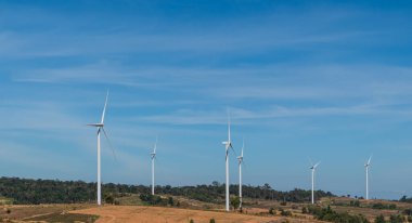 Rüzgar türbinleri mavi arka planda elektrik üretiyor. Sonbahar dağ manzarasında yel değirmeni.