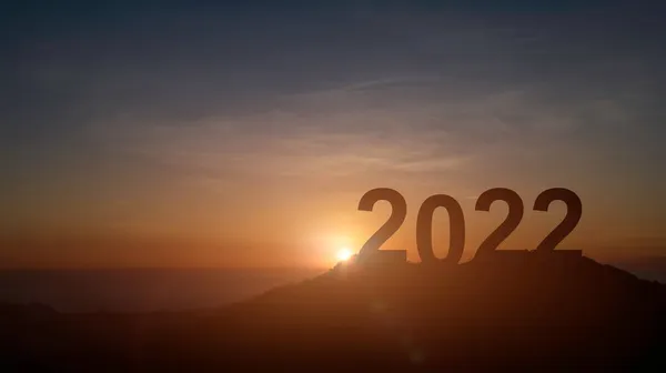 Mutlu yıllar 2022. Dağdaki harflerin silueti güzel bir gün batımı ya da gün doğumu gökyüzü ve bulutlar.