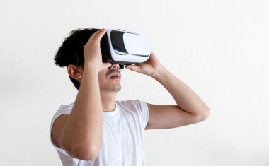 Gri arka planda sanal gerçeklik gözlüğü takan genç bir adam. VR, video oyunu, gelecek, cihazlar ve teknoloji kavramı.