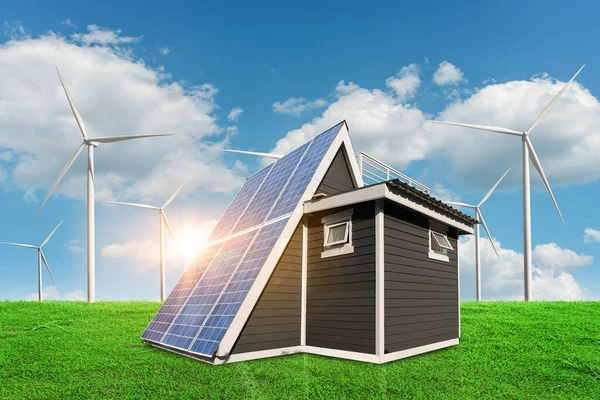 Solar panels on a house roof on green grass with wind turbine and blue sky background. alternative electricity source - sustainable resources concept.