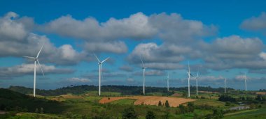 Tepelerdeki mavi gökyüzü arka planlı rüzgar türbinlerinin manzarası. Yenilenebilir enerji kavramı