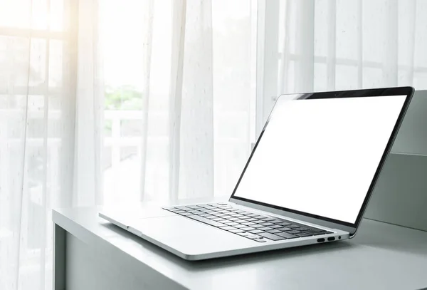 Computer laptop with blank screen on white table in home interior or office background
