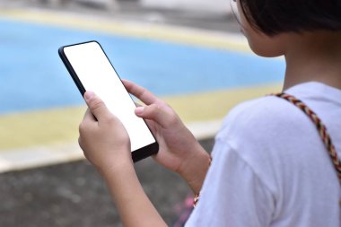 Parkta boş ekranlı akıllı telefonu tutan çocuk..