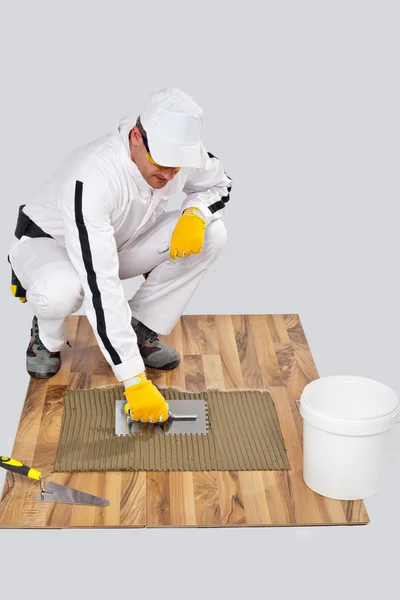 Appling Tile Adhesive with Notched Trowel on a old wood Floor — Stock Photo, Image