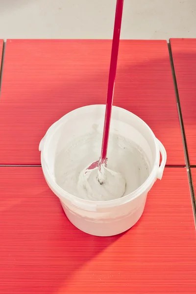 Bucket with mixed grout ready to fill joint on tiles — Stock Photo, Image