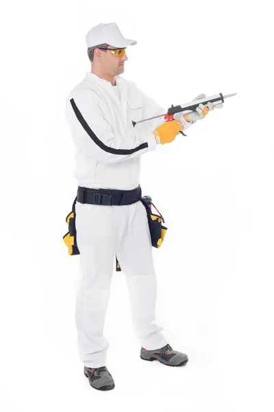 Byggnadsarbetare i vita overaller håller en pistol med silicon — Stockfoto