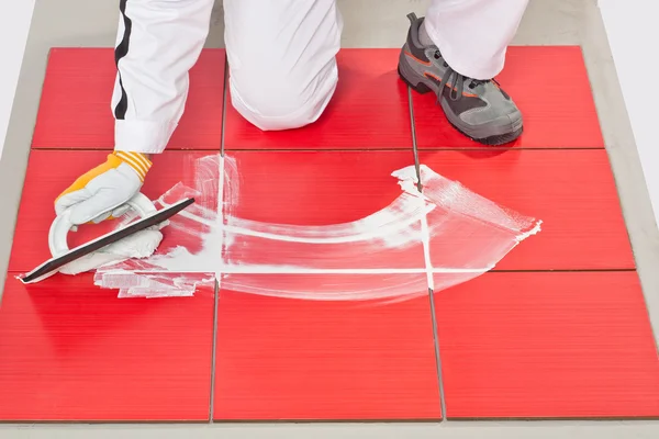 Hand with rubber trowel applying grout tile — Stock Photo, Image