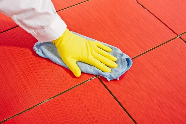 Hand with yellow gloves and blue towel clean red tiles grout — Stock Photo, Image
