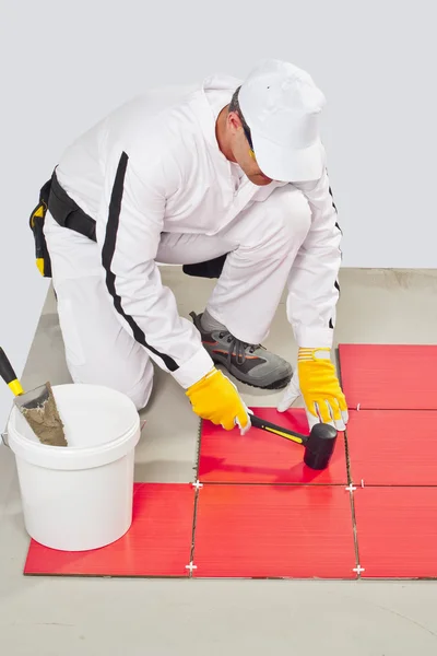 Worker Applies with Rubber Hummer Red Tile on a Floor — Stock Photo, Image