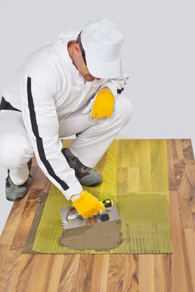 Worker applies tile adhesive with reinforcement mesh — Stock Photo, Image