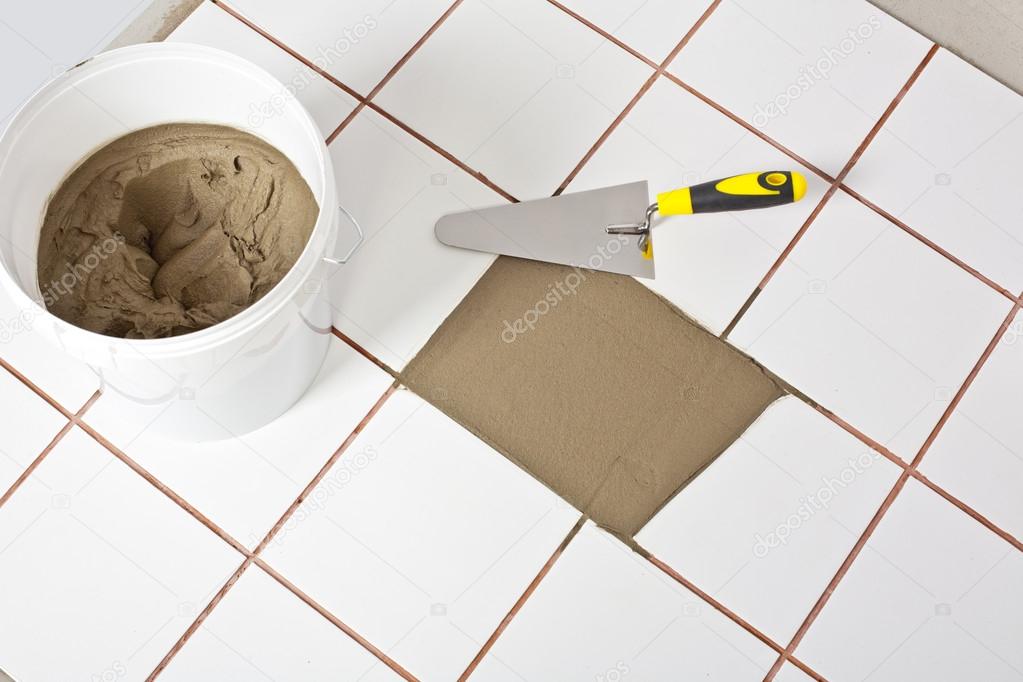 Trowel and old white tiles with tile adhesive