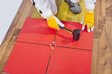 Worker Applies with Rubber Hummer Tile on a wooden Floor clipart