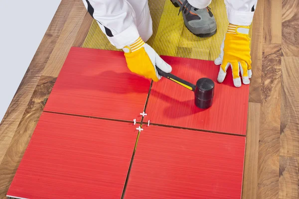 Worker Applies with Rubber Hummer Tile on a wooden Floor — Stock Photo, Image