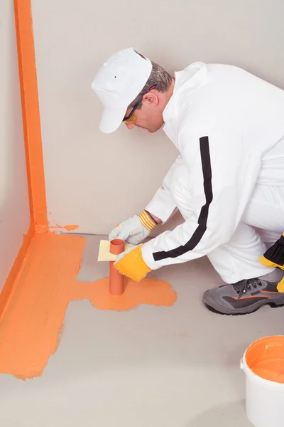 Werknemer borstel toegepast afdichting op de vloer van de badkamer — Stockfoto