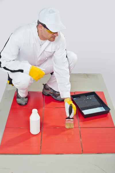 Worker brush primer grout of red tiles — Stock Photo, Image