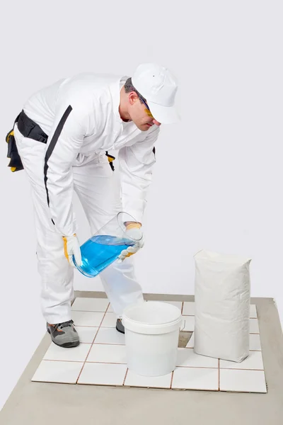 Worker mix tile adhesive bucket of water — Stock Photo, Image