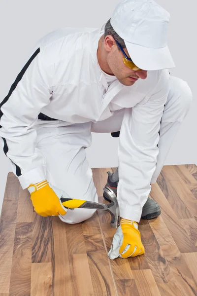 Arbeiter nagelte Nagel mit Hammer auf Holzboden — Stockfoto