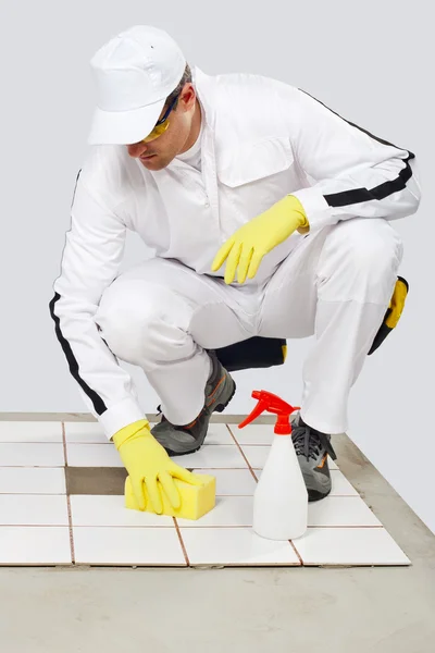 Worker cleans with sponge and spray old tiles floor before tilli — Stock Photo, Image
