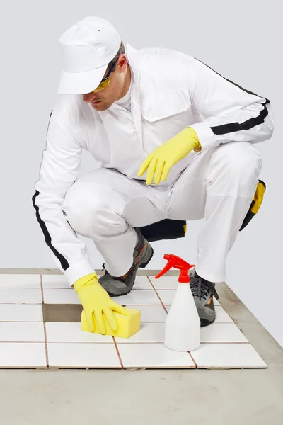 Travailleur nettoie avec éponge et pulvériser les vieux carreaux de sol avant tilli — Photo