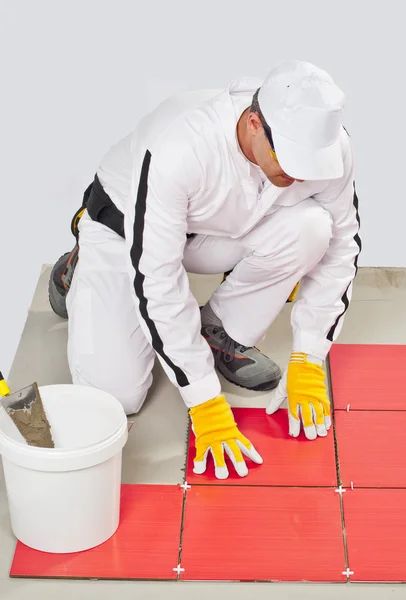 Trabajador con adhesivo de cubo aplicar azulejos rojos — Foto de Stock