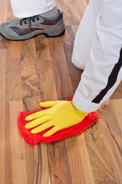 Worker cleans with towel wooden floor before tilling — Stock Photo, Image