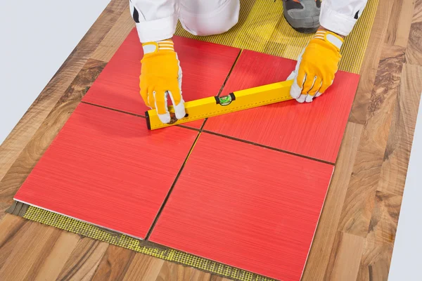 Arbeiter nivelliert Fliesen auf alten Holzboden verstärktem Netz aufgetragen — Stockfoto