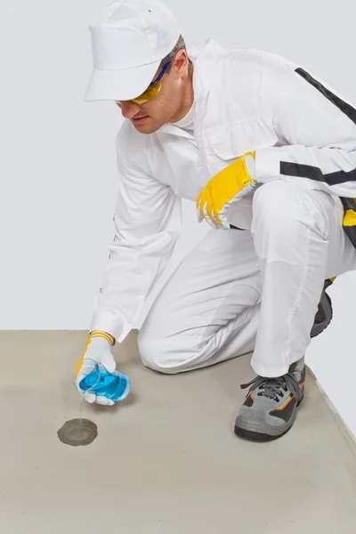 Trabalhador com frasco de vidro de água testando a umidade do cimento — Fotografia de Stock