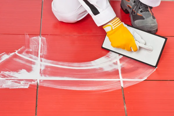 Worker with rubber trowel applying grout tile — Stock Photo, Image