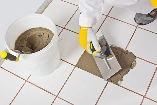 Worker with trowel repairs old white tiles with tile adhesive — Stock Photo, Image