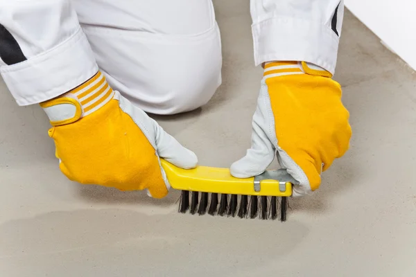 Trabalhador com escova de arame limpa a base de cimento — Fotografia de Stock