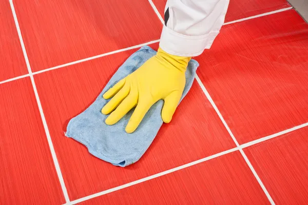 Trabajador con guantes amarillos y toalla azul limpia azulejos rojos lechada —  Fotos de Stock