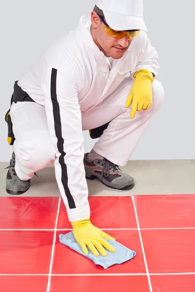 Travailleur avec des gants jaunes serviette bleue propre coulis de carreaux rouges — Photo