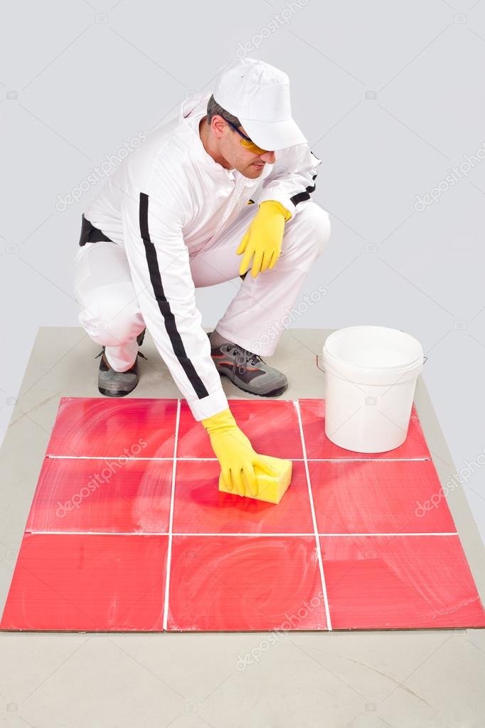 Worker with yellow gloves and yellow sponge clean tiles