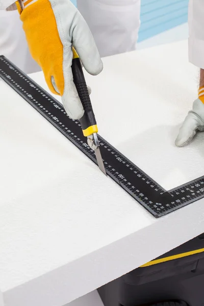 Worker cutting an insulation panel with a scale model knife — Stock Photo, Image