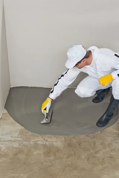 Worker spreading self leveling compound with trowel — Stock Photo, Image