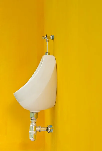 White porcelain urinals on yellow wall — Stock Photo, Image