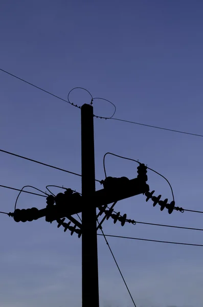 An electrical pole silhouetted against the blue sky — Stock Photo, Image