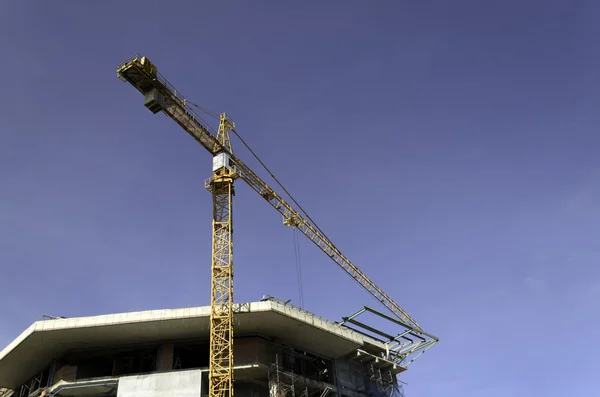 Building crane and building under construction against blue sky — Stock Photo, Image