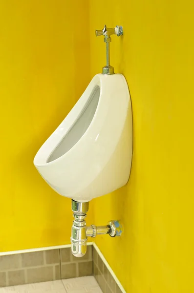 Urinarios de porcelana blanca en la pared amarilla en los baños públicos —  Fotos de Stock