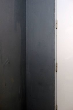 Kapının önünde metal saplı beyaz beton bir duvar..