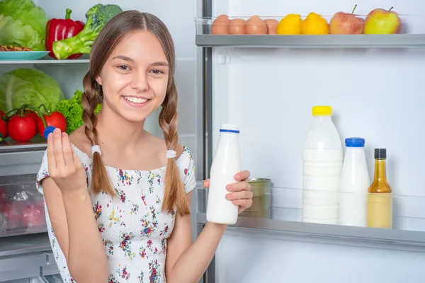 Fille avec de la nourriture près du réfrigérateur — Photo