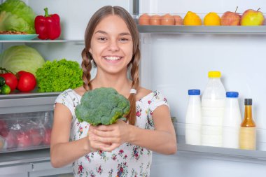 Buzdolabının yanında yemeği olan kız.