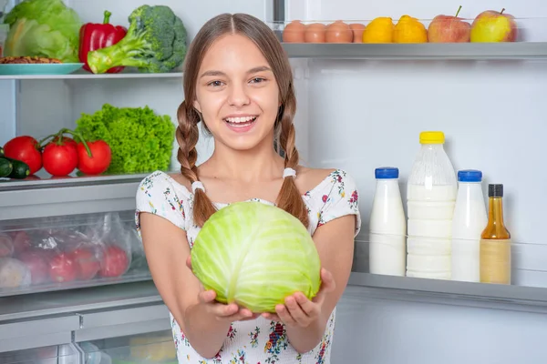 Chica con comida cerca de nevera — Foto de Stock