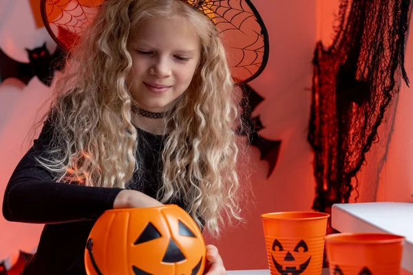 Halloween bambini ragazza con secchi di zucca in cappello costume da strega mangiare caramelle a casa. Pronti per la vacanza dolcetto o scherzetto. — Foto Stock