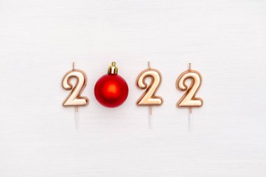Mutlu yıllar ve Noel 2022 kutlamaları. Festivalin altın numarası 2022 mum beyaz zemin üzerinde Noel kırmızı top