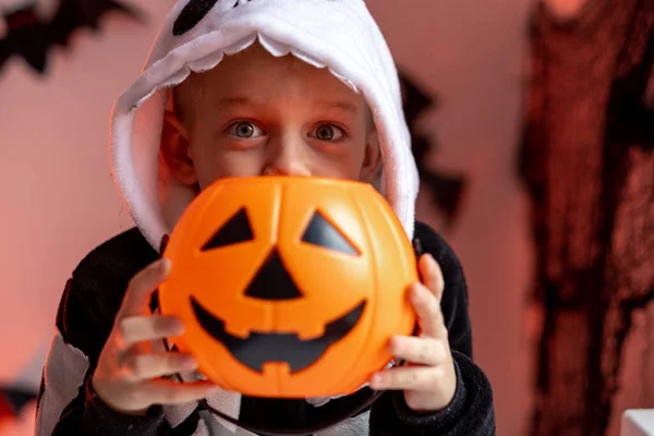 Niño de Halloween con cubos de caramelo de calabaza en traje de esqueleto en casa. Listo para engañar o tratar vacaciones —  Fotos de Stock