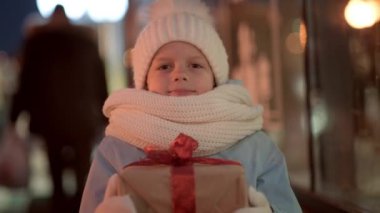 Hediyeler kutusuyla portre çocuk geleneksel Noel pazarında Noel vitrininde alışveriş yapıyor ve hayal kuruyor. Xmas Çocukluk Tatili Konseptini Sunar.